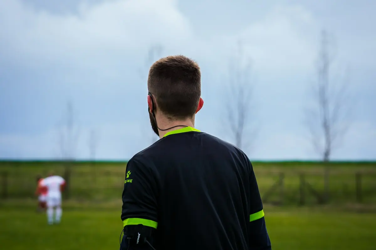 Un árbitro de fútbol sigue el partido desde el césped.