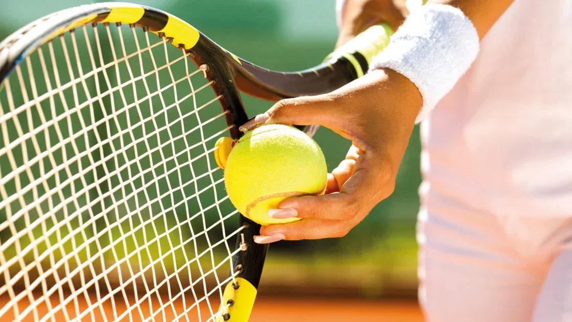 Tenista golpea con potencia en pista bajo la luz del torneo.